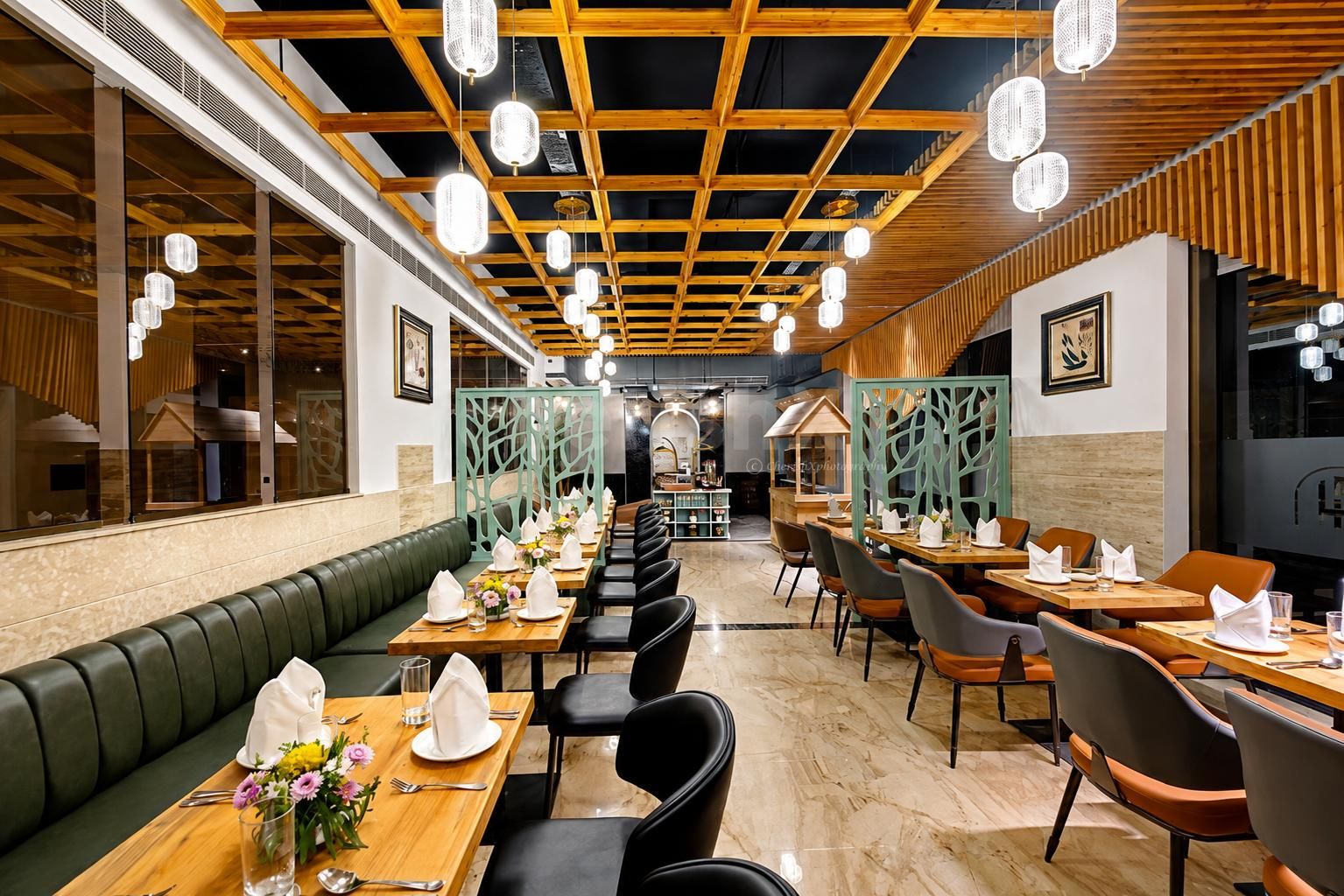 Modern hotel restaurant with elegant seating, wooden interiors, ambient pendant lighting, and beautifully arranged dining tables.