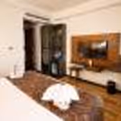 Elegant hotel room with king-size bed, warm lighting, modern interiors, and decorative towel art.