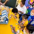 Kids painting during a figurine painting activity. Kids are making figurines out of things they have made themselves, in painting aprons.
