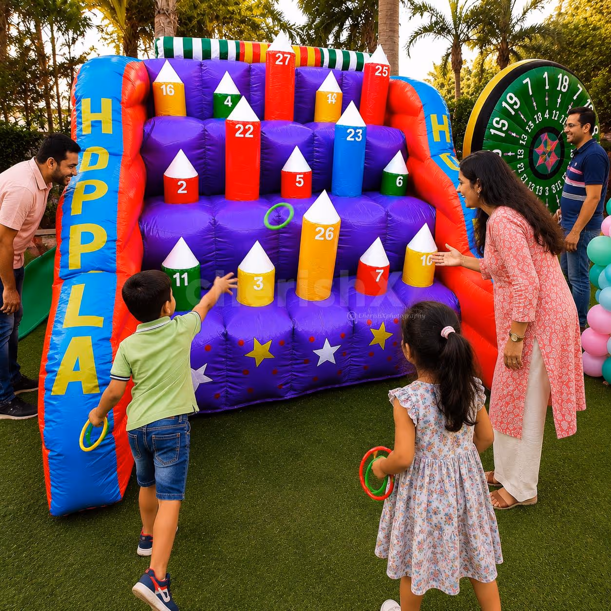 Children engaged in a big inflatable hoopla target game at an outdoor birthday party.