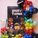 Kids birthday setup themed around Roblox with clusters of red, blue, green, yellow and black balloons in a gaming backdrop.