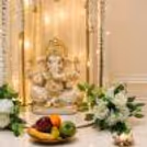 Close-up of a top flower arrangement with white flowers, green leaves and a hanging golden bell.