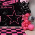 Pink and black photo backdrop, balloon arch and matching floor flex with music theme cutouts.