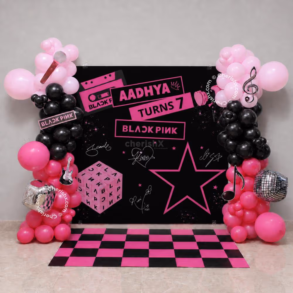 Birthday Backdrop for BLACKPINK with pink and black balloon arch, pink and black flex, checkered floor pattern.