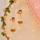 Pearl jewellery hanging against a cheerful wall of coloured flowers and bell strings.
