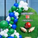 Personalised wall for a cricket birthday party. A colourful bunch of balloons creates the wicket