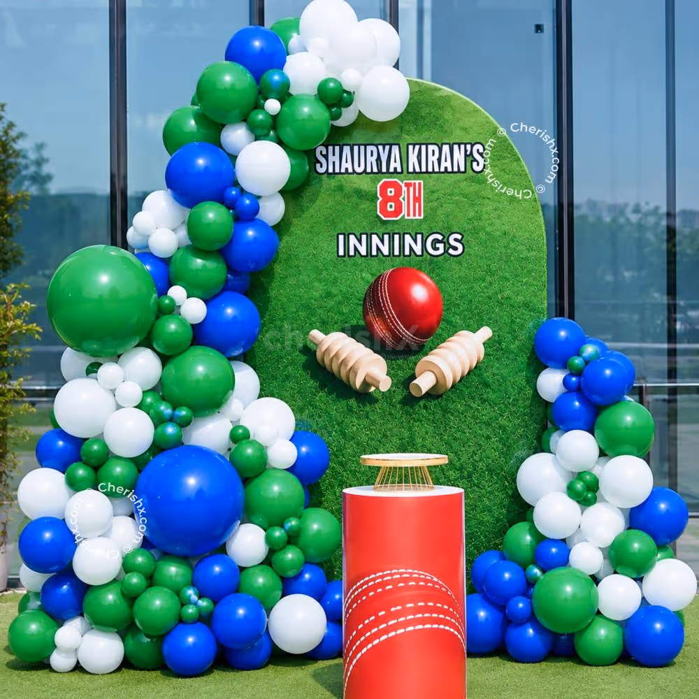 Personalised cricket background with green, blue and white balloon setup as a cricket-themed birthday party decoration.