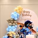 Cricket-themed birthday decoration, 2 Virat Kohli cutouts and soft blue and beige colored multiple layer balloon clusters.