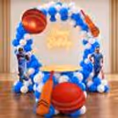 Cricket Lover Ring Stand Birthday Decor with a blue and white balloon arch, cricket bat and ball cutouts and a Happy Birthday neon light.