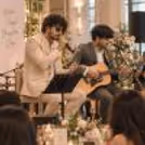 Live singer and guitarist entertaining an audience at an evening event with a professional music setup.