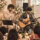 Live music duo performing at a daytime banquet event, with a singer and guitarist entertaining wedding guests.
