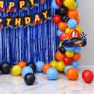 Hot Wheels Birthday Party Decor With Red, Yellow, Blue And Black Balloons Surrounding A Festive Background.