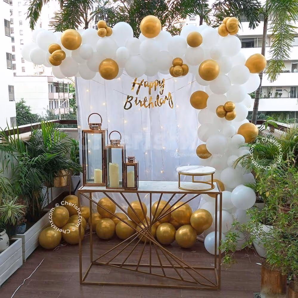 White and Gold Birthday Decoration with Balloon Backdrop, Fairy Lights, Candle Lanterns and Cake Table Setup – Elegant Birthday Party Decor for Home, Terrace or Outdoor Celebration