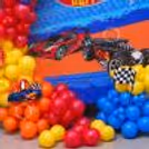Hot Wheels birthday decoration with racing themes on red, blue, orange and yellow balloon clusters.