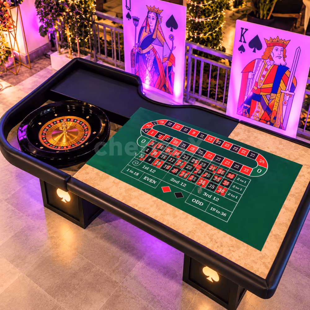 Luxury roulette table setup at an event with a green felt playing surface, roulette wheel, illuminated suit symbols and vibrant purple lighting.
