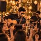 Close-up of a live guitarist playing for an engaged audience at a beautifully lit event.