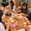 participants creating handmade wax candles with dried flowers and decorative elements during a candle-making workshop.