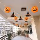 Halloween balcony decoration with orange pumpkin lanterns, hanging witch hats and fairy lights.