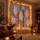 Halloween window decoration with floating white fabric ghosts, warm lighting, and professionally styled festive decor by CherishX.
