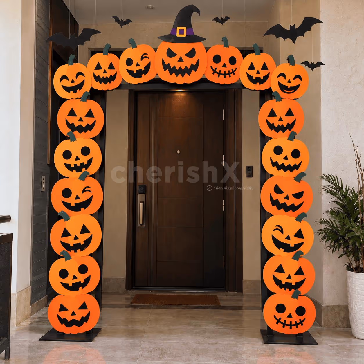 Spooktacular Halloween entrance decoration with colourful pumpkin cutout arch, witch hat and hanging black bats for home and party entrances.