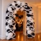 Halloween entrance balloon decoration with black and white balloons, mummy-style nylon net fabric and spooky eyes, professionally installed by CherishX.