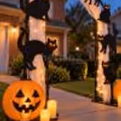 Black cat Halloween entrance decoration with pumpkin paper lanterns, LED candles and white net fabric on an arch stand.