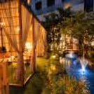 Private luxury gazebo dinner setup with elegant drapes, glowing candles, and floral decorations.