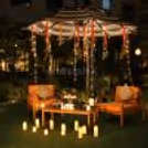 Romantic outdoor candlelight dining setup with a glowing LOVE sign, white roses, and warm fairy lights