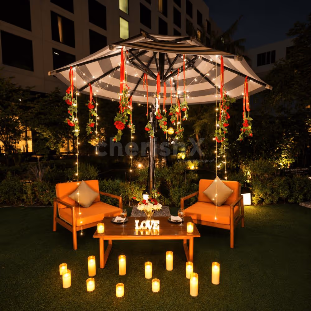 Premium garden date night decor featuring orange lounge chairs, elegant table styling, and candlelight.