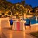 Romantic poolside dining experience at The Grand Delhi with an elegantly decorated table, candlelight, and beautiful garden surroundings.
