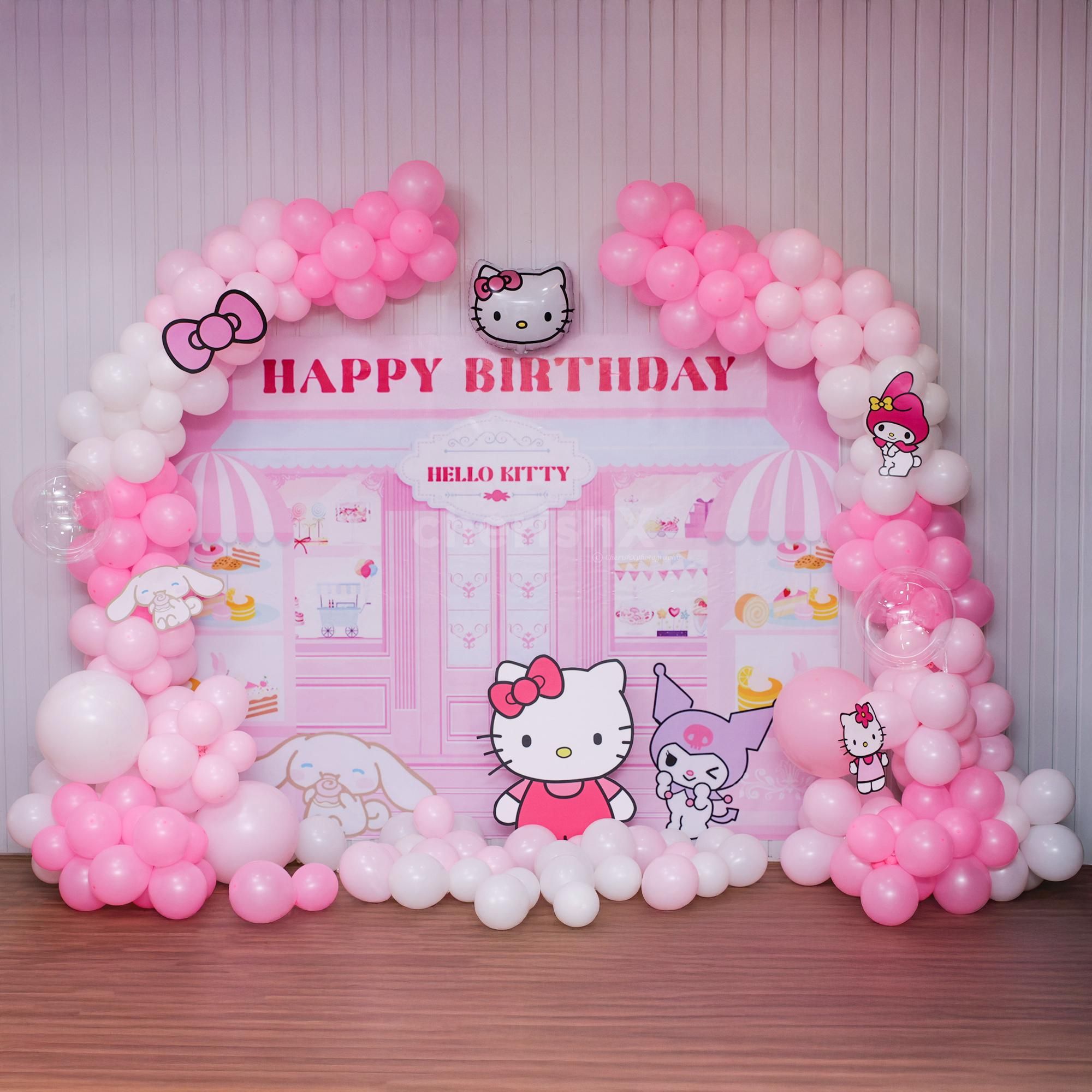 Soft pastel pink Hello Kitty backdrop creates a joyful setting.