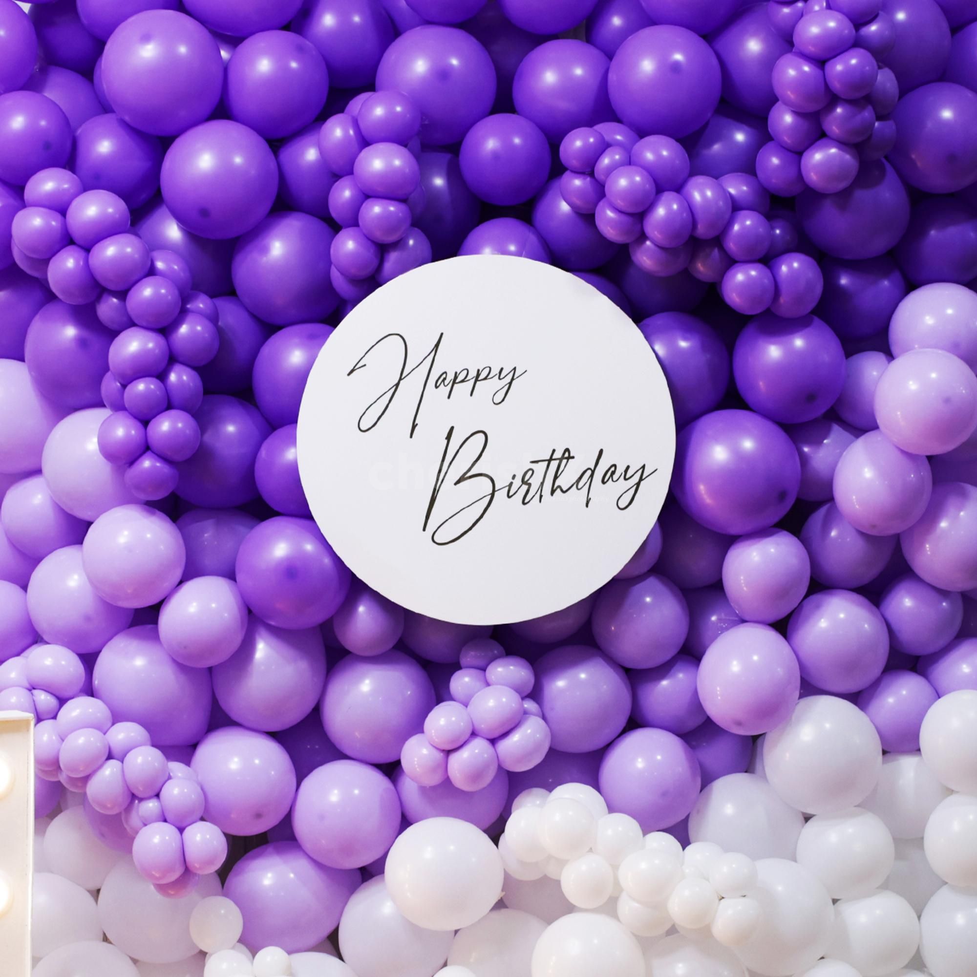 Stylish birthday setup with purple and white balloons wall and sparkling LED digital.