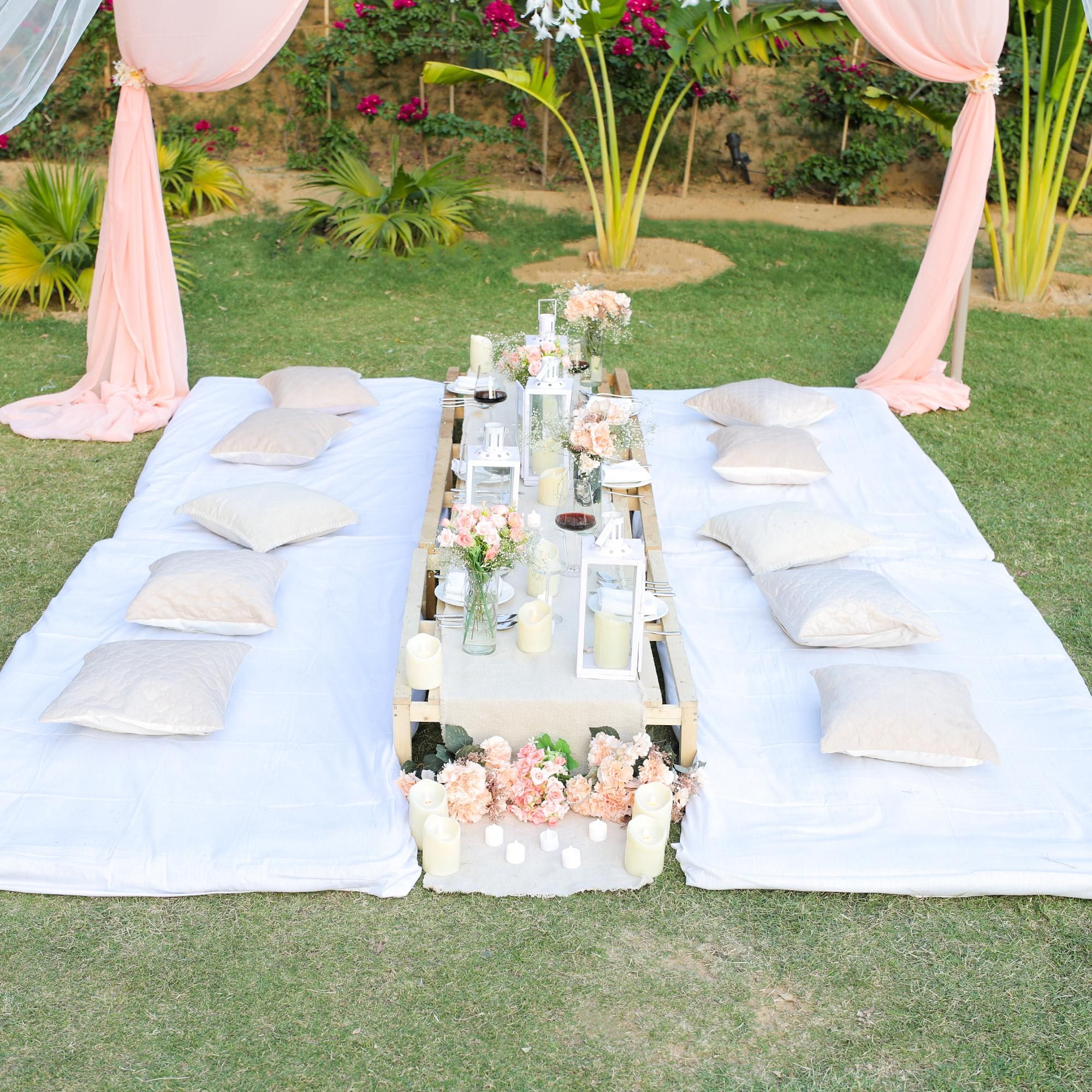 A warm picnic arrangement with cushions, bedsheets, and soft candles.