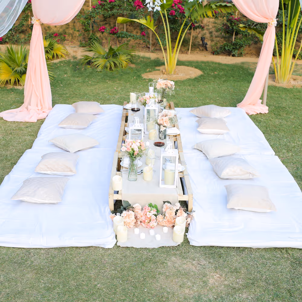 A warm picnic arrangement with cushions, bedsheets, and soft candles.