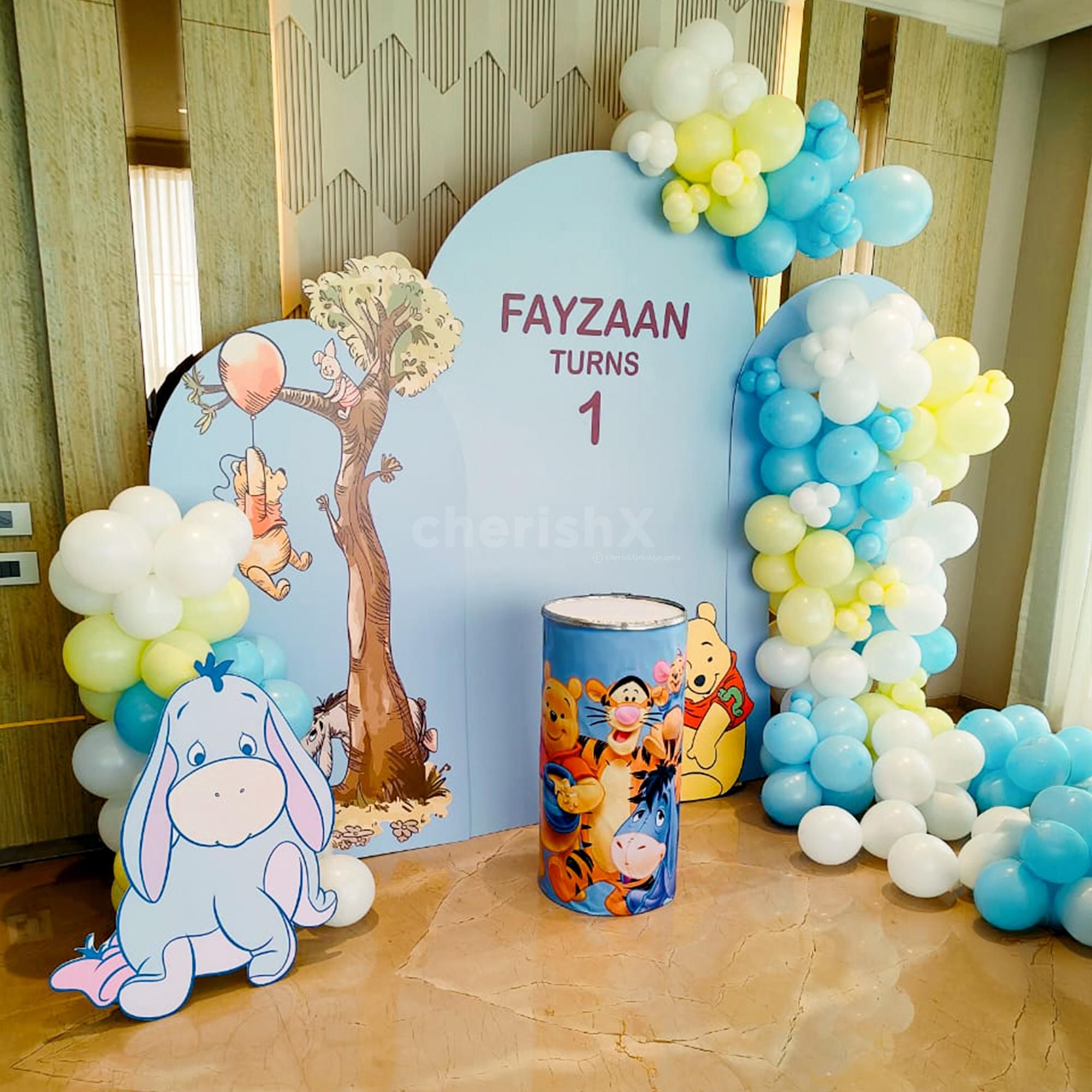 Pastel yellow, blue, and white balloon arch for soft light.