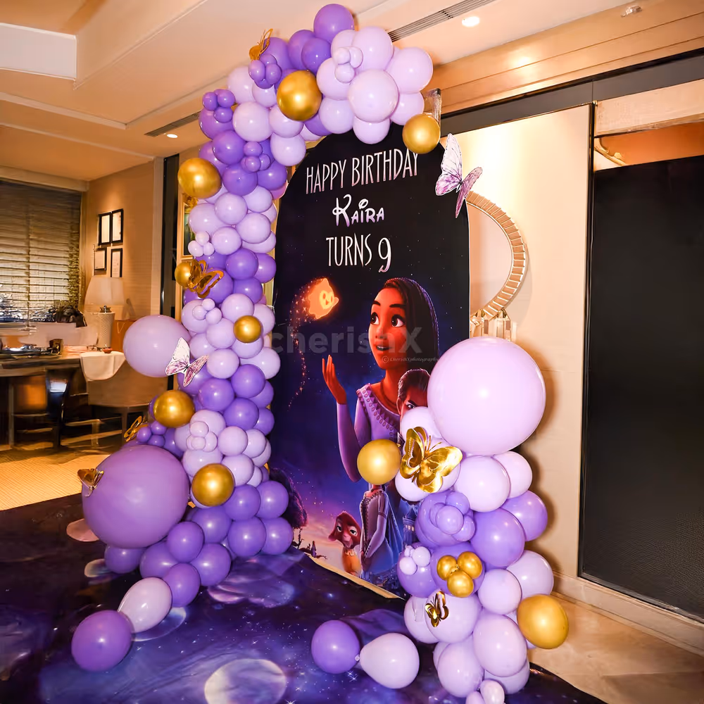 Sheer balloon arch with golden accents and butterfly motifs.