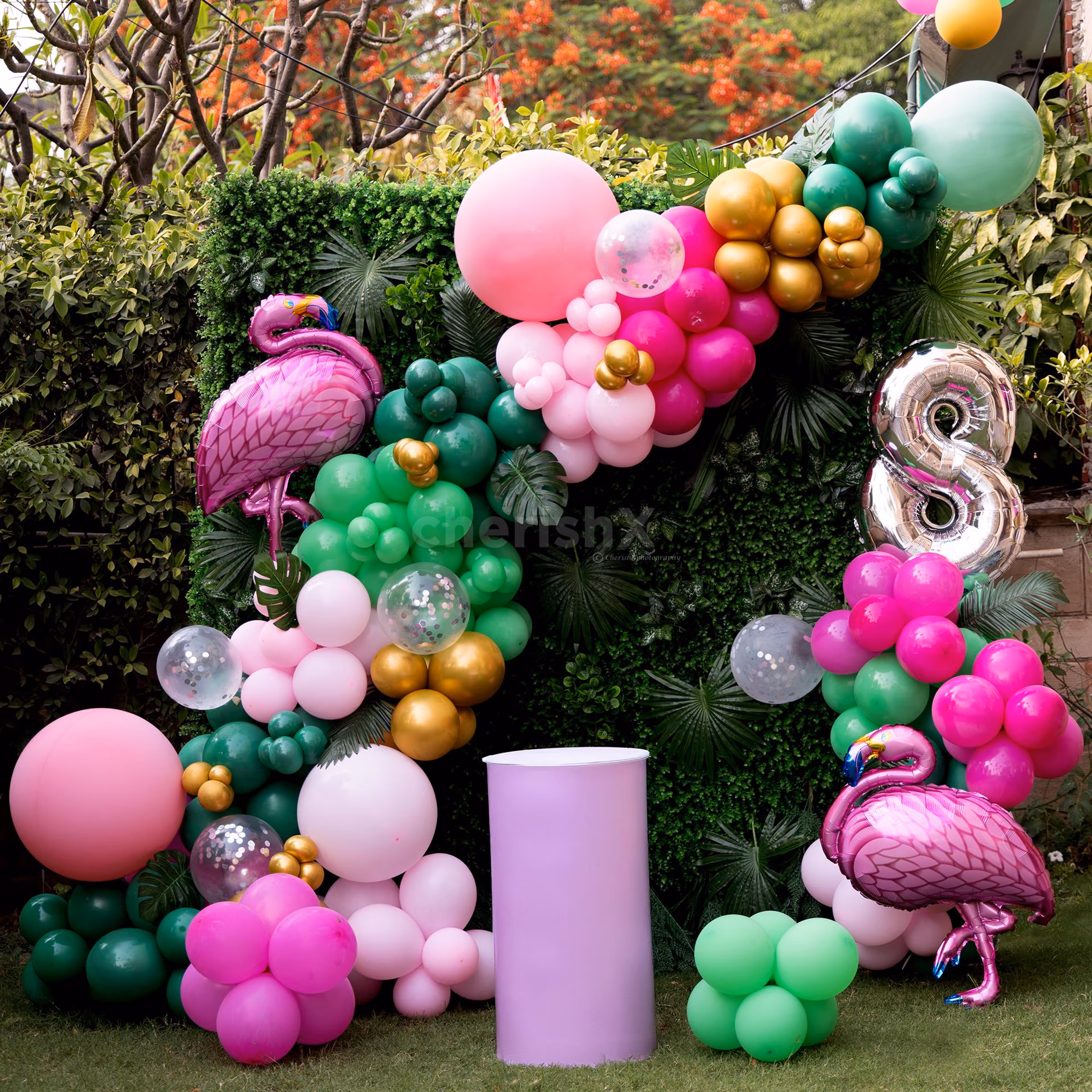 A green tropical backdrop and colorful balloons.