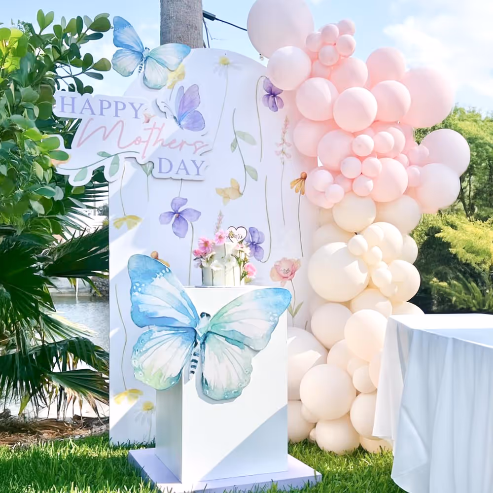 Pastel pink balloon arch surrounds a Mother's Day banner.