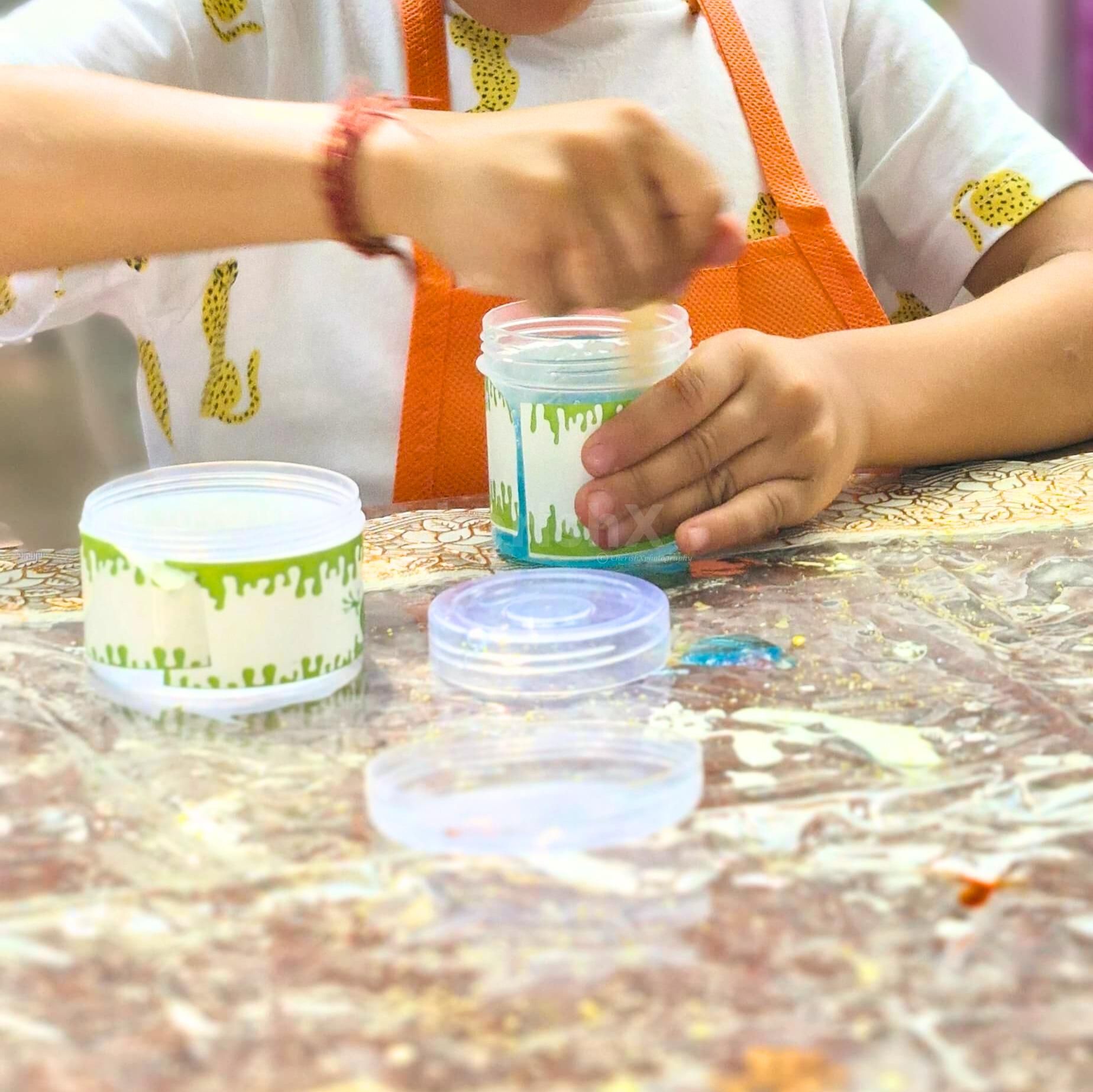 Kids mixing magic colours into slime bowls