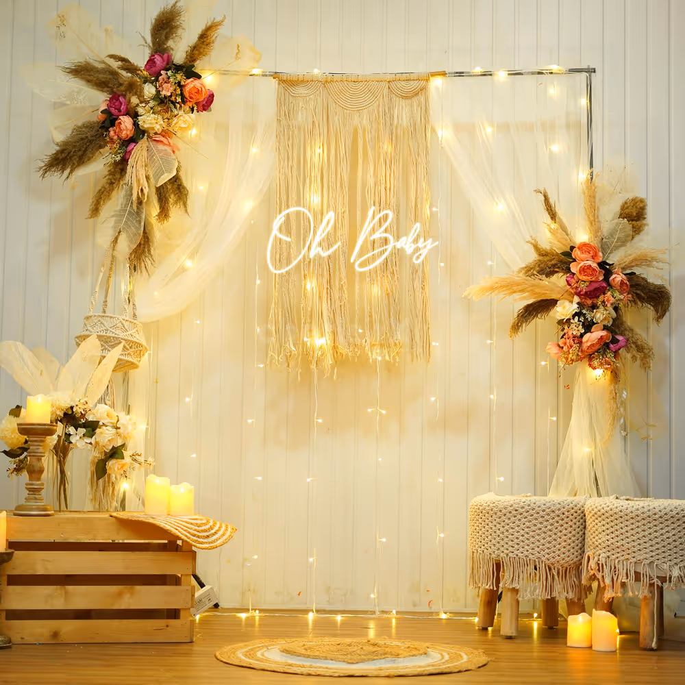 Pampas and boho drapery around a warm "Oh Baby" neon sign.