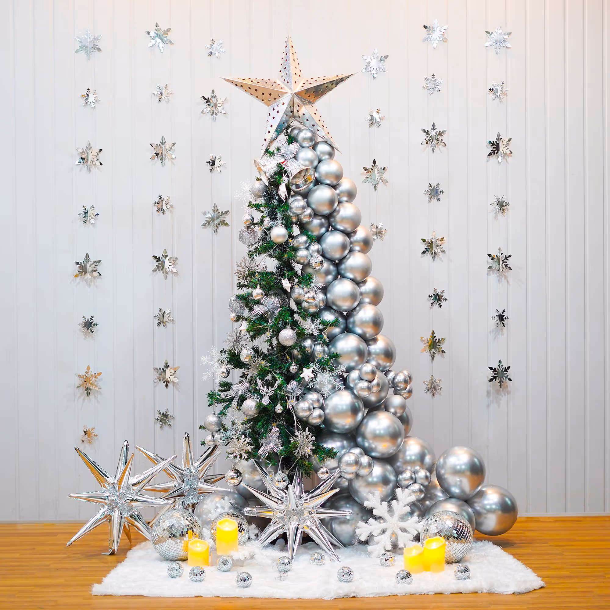 A beautiful Christmas tree decoration features a 6-ft non-pine tree decked out with silver chrome balloons, LED lights, and a silver paper star.