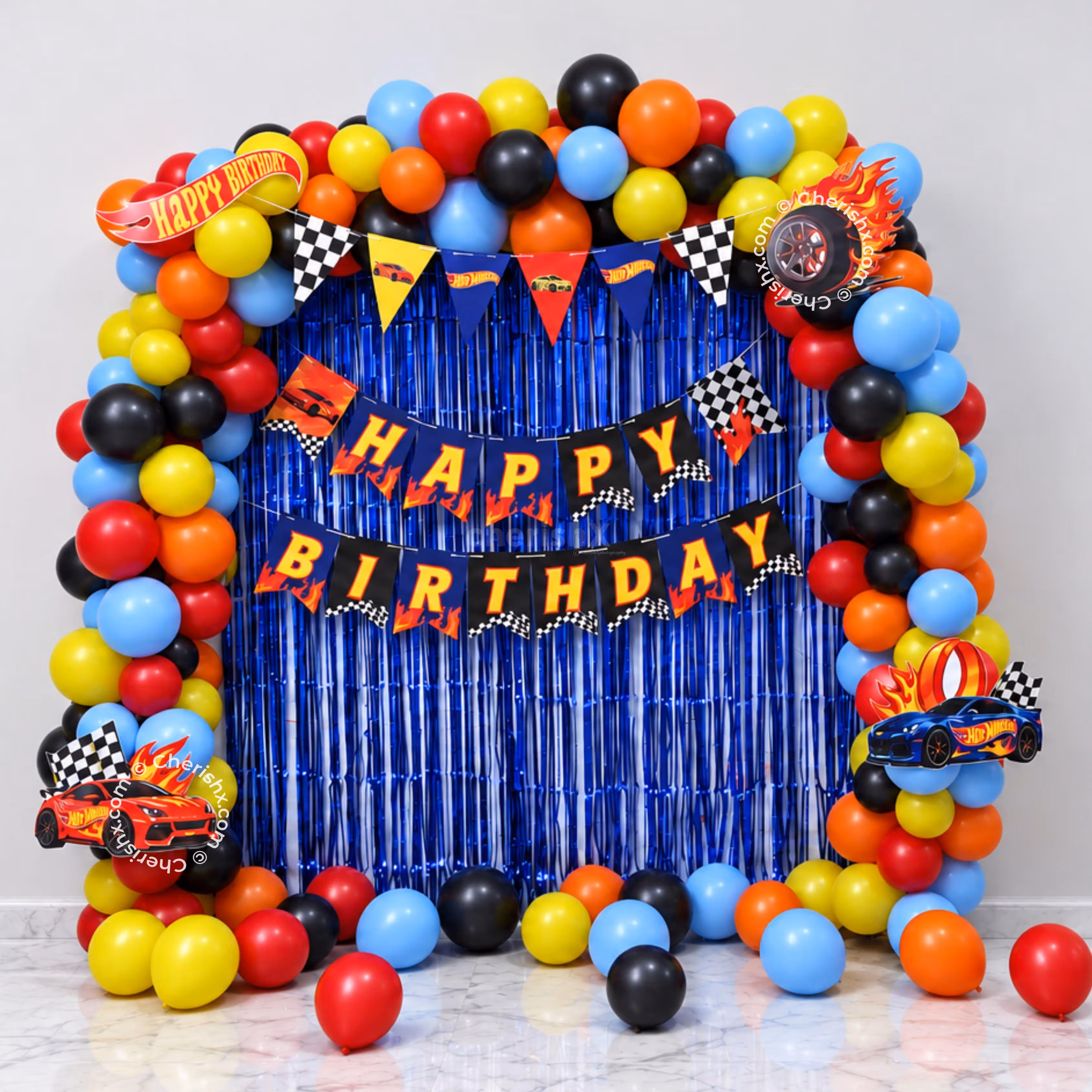 Hot Wheels Birthday Decoration With Multicolour Balloon Arch, Racing Cutouts And Dark Blue Background.