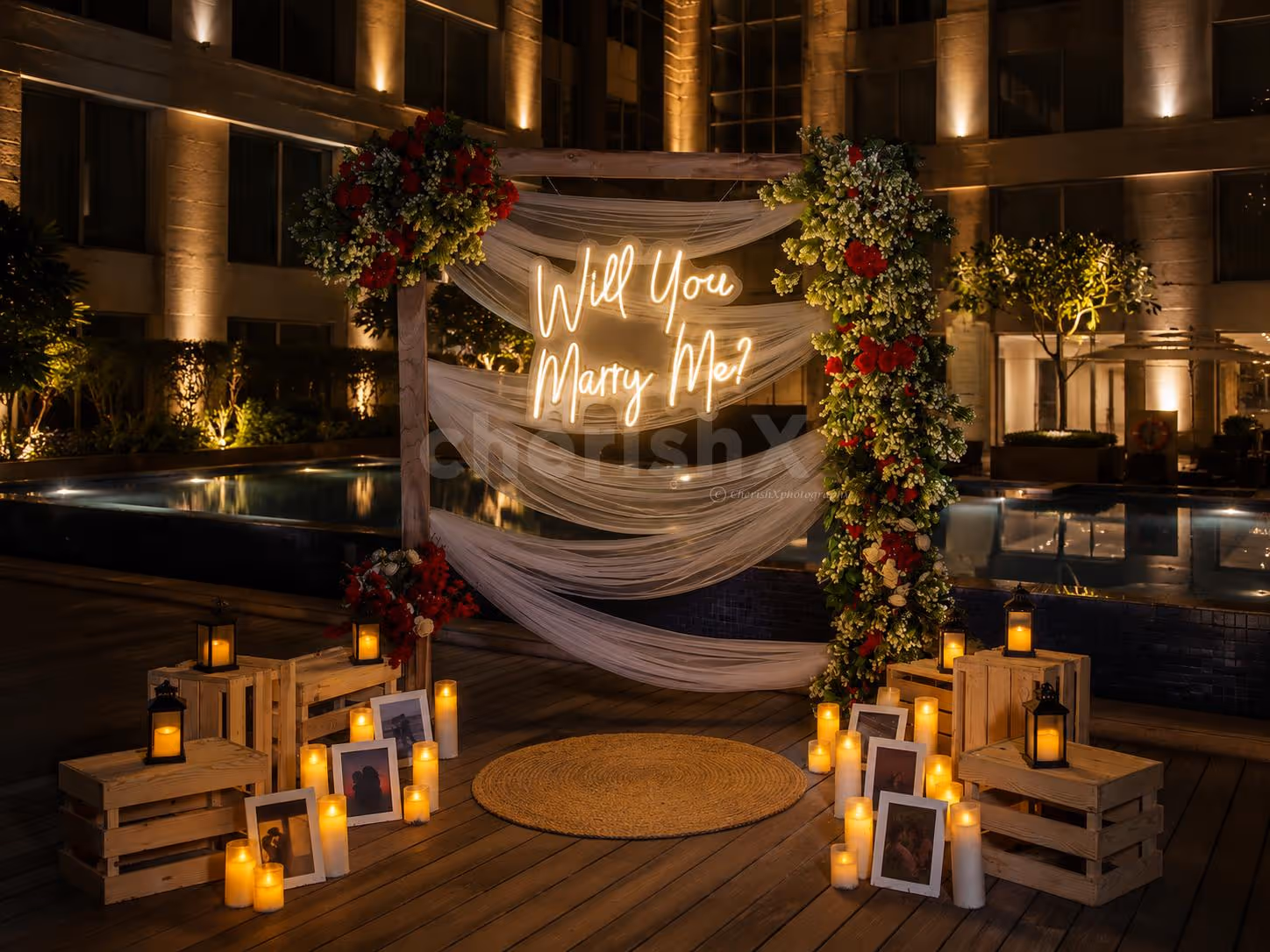 Luxury poolside proposal setup with romantic candlelight décor, flower petals, and private dining arrangement for couples.