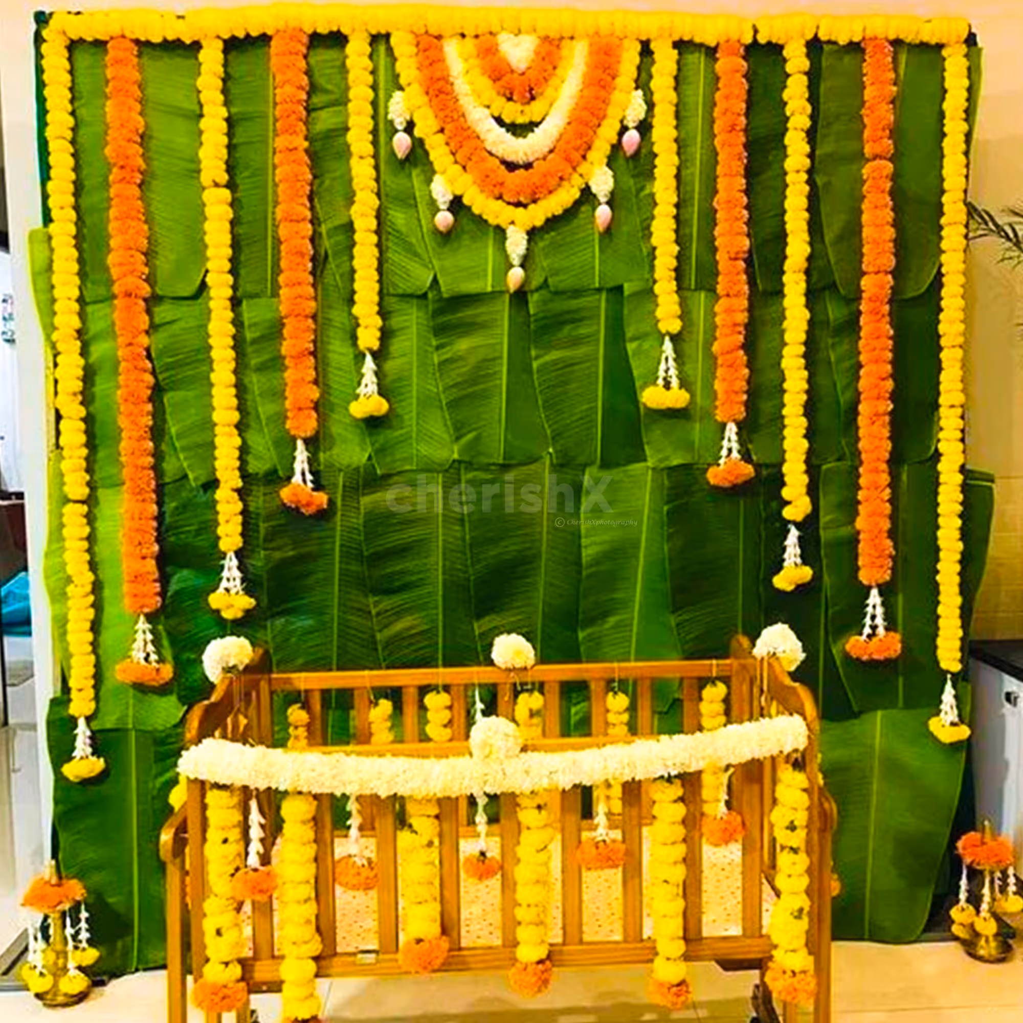 A mesmerizing backdrop adorned with vibrant banana leaves and orange marigold flowers creates a captivating ambience at the naming ceremony.
