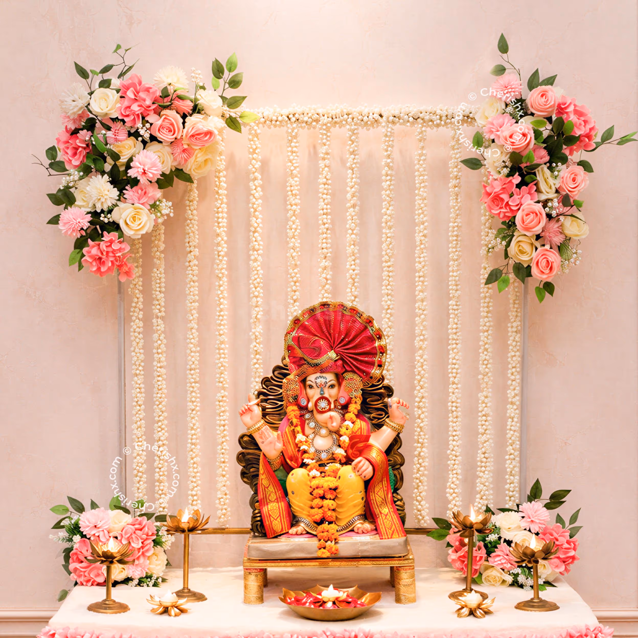 Ganpati idols with white jasmine strings on a golden background with pastel pink flowers